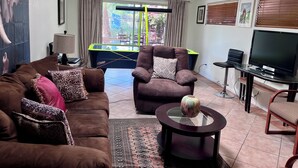 A living room with a brown sofa, a glass coffee table, a TV, and a pool table. - Charming Villa House 3-bedroom with pool & jacuzzi, AC in beautiful San Marcos (San Marcos)