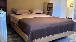Een slaapkamer met een bed, een houten nachtkastje, een plank en een radiator.