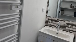 Een moderne badkamer met een wit wastafelmeubel, een spiegel en een handdoekhouder.