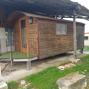 A wooden cabin with a porch, a door, and a window. - Caravan in farmhouse (Arles)