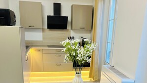 A modern kitchen with built-in appliances, a dining table with placemats, and a vase with flowers. - Luxury design apartment Cannes Centre - 2 mn Palais du Festival and Croisette (Cannes)