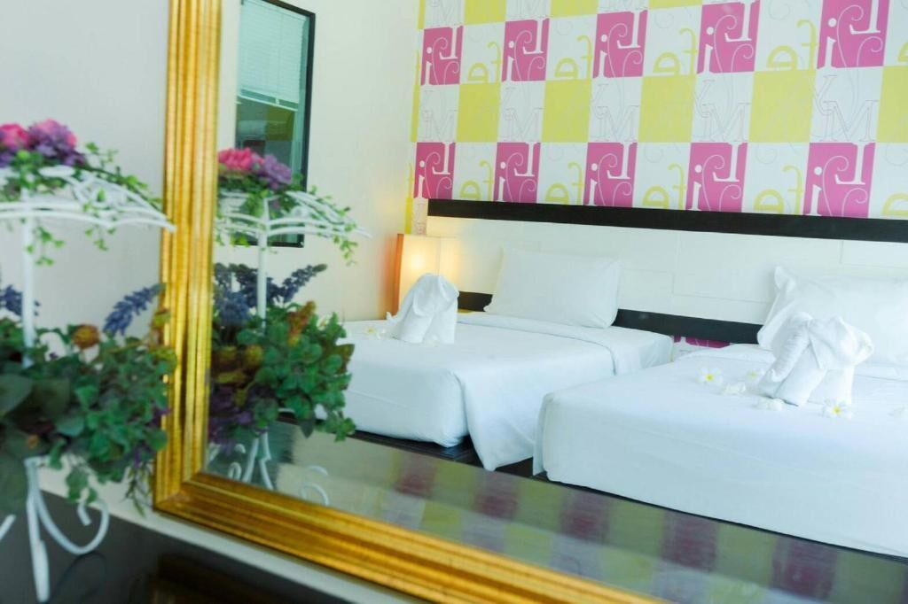 A hotel room with two beds, a large mirror, and a wall with a checkered pattern.