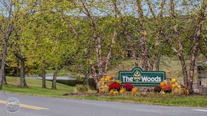 A sign for 'The Woods' with autumn decorations. - Thistlewood Cottage - Screen Porch | Fireplace | Golf | Pool Pass | Woods Resort | Grill (Hedgesville)