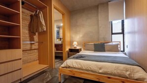Een slaapkamer met een houten bed, een garderobe en een klein nachtkastje met een lamp.