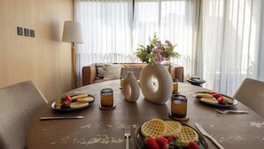 Een eettafel gedekt met wafels, aardbeien en een bloevas.