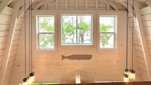 A room with a sloped ceiling, wooden beams, and a large window with three panes.