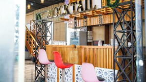 A bar area with a wooden counter, metal railings, and three chairs. - AARYA HOTEL & SPA Jim Corbett (Ramnagar)