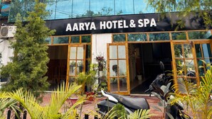 A modern hotel with a large glass facade reflecting trees and sky. - AARYA HOTEL & SPA Jim Corbett (Ramnagar)