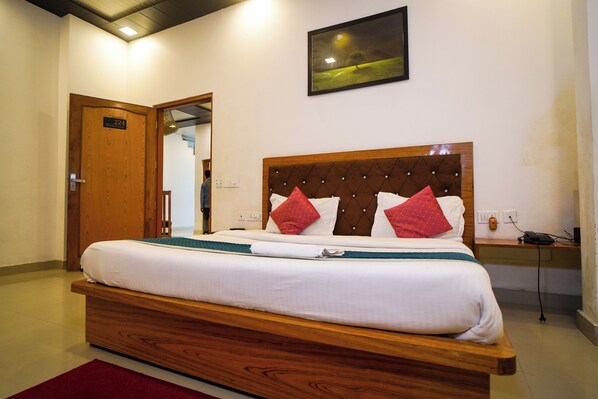 A hotel room with a wooden bed, a night light, and a painting on the wall.