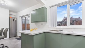 Eine moderne Küche mit integrierter Kochinsel, einem Edelstahlkühlschrank und einem Fenster mit Blick auf die Stadt.