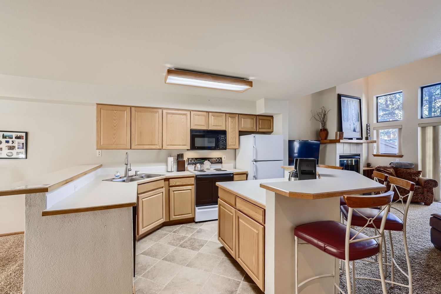 A modern kitchen with wooden cabinets, a central island, and bar stools.