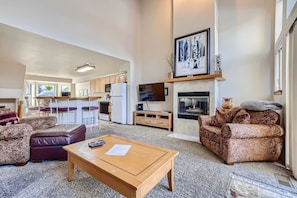 A spacious living room with a fireplace, a kitchen in the background, and a dining area. - New Property! Walk to the heart of downtown and the Lift (Breckenridge)