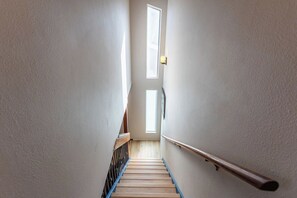 A narrow stairway with wooden steps and a metal handrail, leading to a door with a window above. - C3 On The Tee - 2 Bed Condo on the Golf Course (Estes Park)