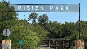 A sign for Risien Park with a closed gate and a dirt road leading through. - Burnham's Lodging (San Saba)