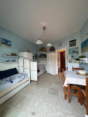 Ein kompakter Wohnbereich mit Bett, Sofa, Esstisch und Küchenzeile.