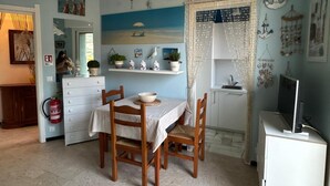 A compact kitchen with a dining table and chairs, a small refrigerator, and a TV on a cabinet. - Cozy accommodation a short walk from the sea and downtown with private parking space (Finale Ligure)