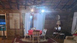 Ein rustikaler Raum mit Holzboden, einem Esstisch mit Stühlen, einer Couch und einer Chandelüstere.