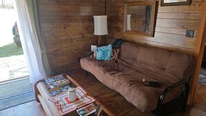 Ein Holzinnenraum mit einem braunen Sofa, einem Tisch mit Tasse und Buch, sowie einem gerahmten Bild an der Wand.