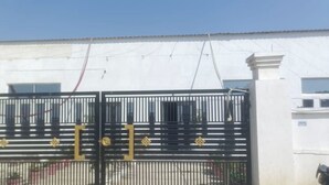 A gated entrance with a metal gate and a white building in the background.