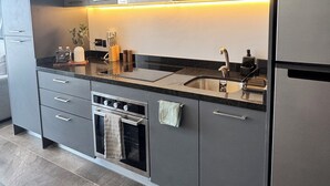 Una cucina moderna con mobili grigi, un frigorifero in acciaio inox, un forno integrato e un lavello con un rubinetto.