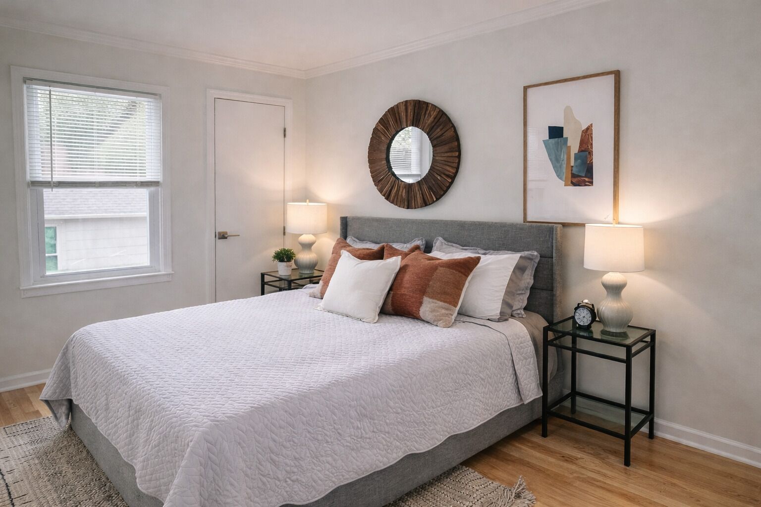 Une chambre à coucher avec un lit, des tables de chevet, un miroir et un tableau encadré au mur.