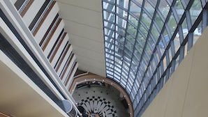 A high-ceiling atrium with a central circular design, large windows, and a modern architectural style. - Tropical Executive Suíte Flat 1001 | Ponta Negra | (Manaus)