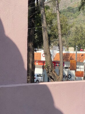 A building with a pink exterior, trees, and a parked car. - New Private Suite with Garage and Own Main Entrance. (Pátzcuaro)