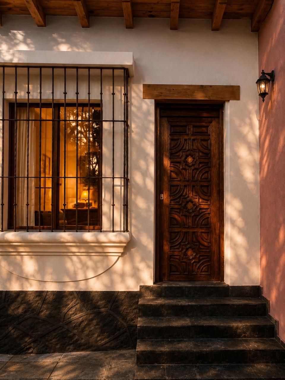A wooden door with intricate carvings, a window with metal bars, and a stone staircase leading to the entrance.