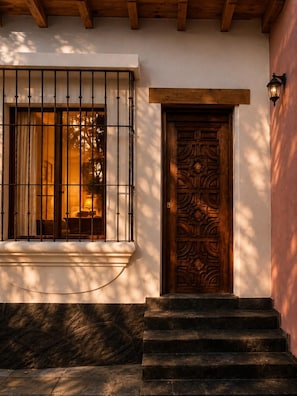 A wooden door with intricate carvings, a window with metal bars, and a stone staircase leading to the entrance. - Fully Equipped Private Suite with Garage and Private Entrance, Very Close to Downtown Pátzcuaro (Pátzcuaro)