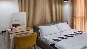 A modern hotel room with a bed, a desk with a computer, a chair, and a mirror. - Unit 706-One Bedroom Unit at One Pontefino Tower (Batangas City)