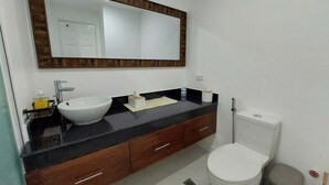 A bathroom with a white sink, dark countertop, wooden vanity, and a large mirror above the sink. - Unit 706-One Bedroom Unit at One Pontefino Tower (Batangas City)
