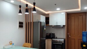 A modern kitchen with a dining area, featuring a refrigerator, stove, and pendant lights. - Unit 706-One Bedroom Unit at One Pontefino Tower (Batangas City)