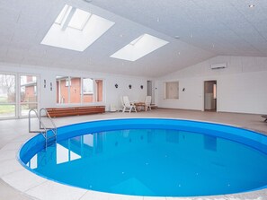 A large indoor swimming pool with a clear view of the sky through skylights, surrounded by white walls and a few seating areas. - 4 Star Holiday Home in Allingabro (Allingåbro)