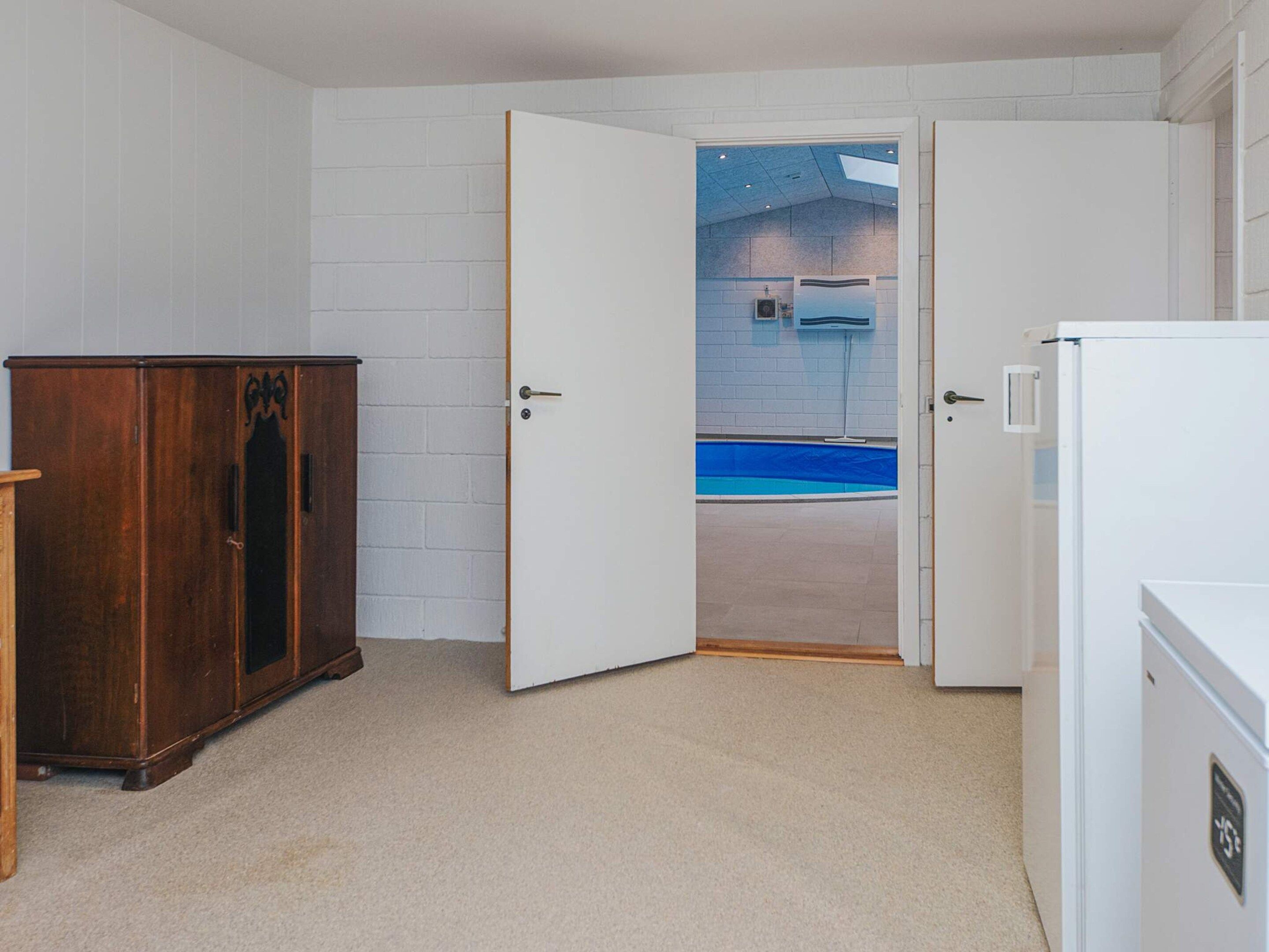 A room with a white brick wall, a wooden cabinet, and a white refrigerator.