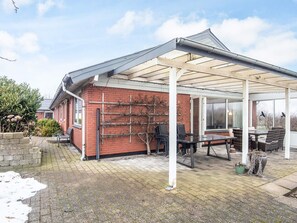 A covered patio with a brick wall, outdoor seating, and a pergola.