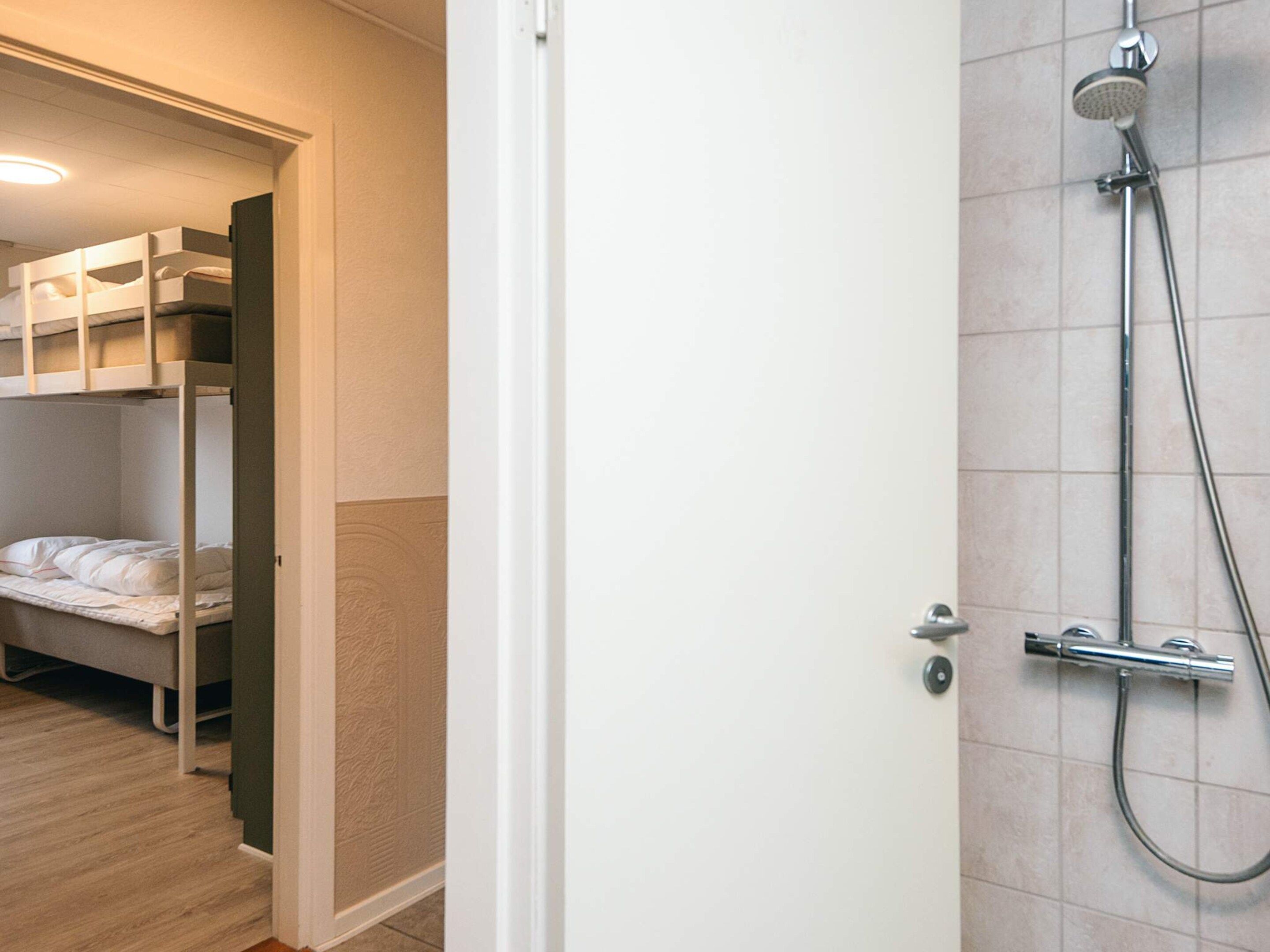 Ein Hotelzimmer mit Dusche, einer Etagenbett und Holzboden.