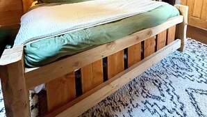 Una cama de madera en una habitación con techos inclinados y paredes de madera.