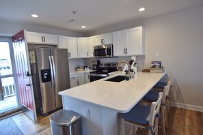 A modern kitchen with white cabinets, stainless steel appliances, and a central island with bar stools.