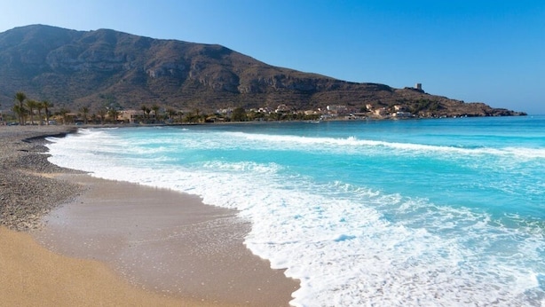 A beach with clear turquoise waters, a pebbly shore, and a mountain in the background. - Modern, Stylish Beach Apartment with Stunning sea views, Pools & Ultrafast Wi-Fi (La'Azohia)