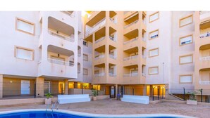 A multi-story building with a swimming pool in the foreground. - Modern, Stylish Beach Apartment with Stunning sea views, Pools & Ultrafast Wi-Fi (La'Azohia)