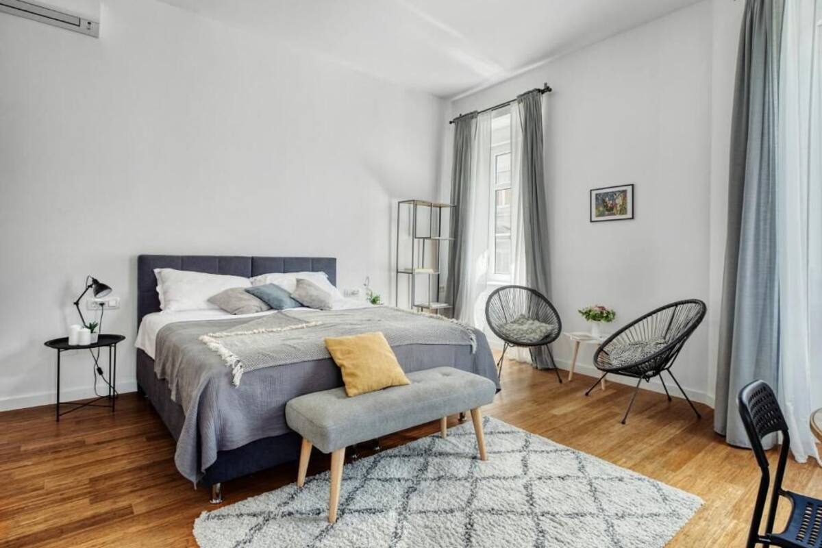 Ein Schlafzimmer mit Bett, Nachttischen, einer Bank und Stühlen.