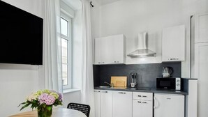 A modern kitchen with white cabinets, a black countertop, a microwave, and a coffee maker. - Berry Berry studios by Flat White (Zagreb)