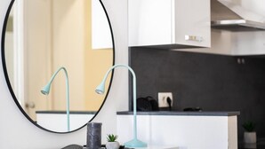 A modern kitchen with a round mirror, a teal pendant light, and a black countertop. - Berry Berry studios by Flat White (Zagreb)