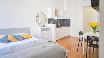 Un dormitorio moderno con cama, mesita de noche y una pequeña kitchenette.