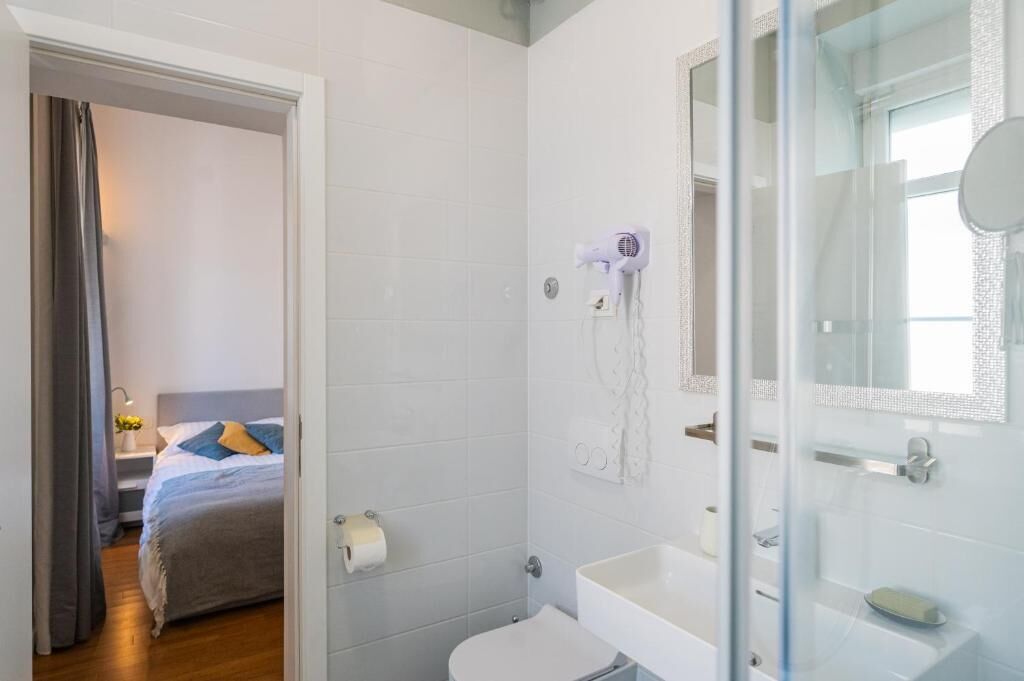 Un bany modern amb una cabina de dutxa de vidre, un lavabo blanc i un vàter.