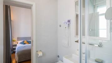 Un bany modern amb una cabina de dutxa de vidre, un lavabo blanc i un vàter.
