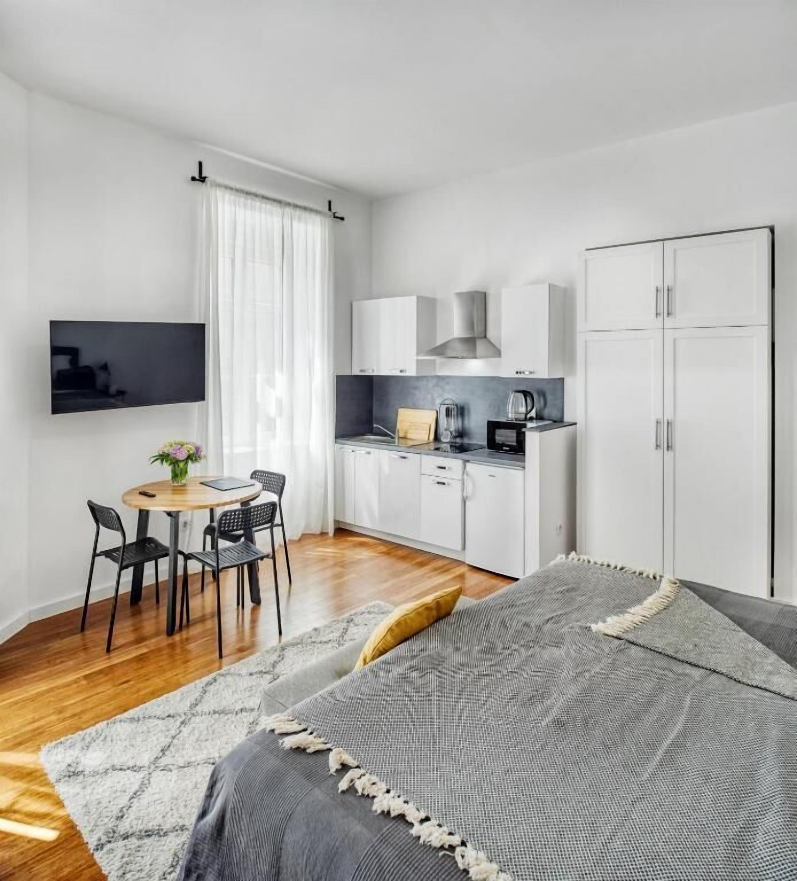 A modern, compact room with a kitchen, a dining area, and a bed.