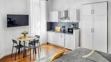A modern, compact room with a kitchen, a dining area, and a bed.