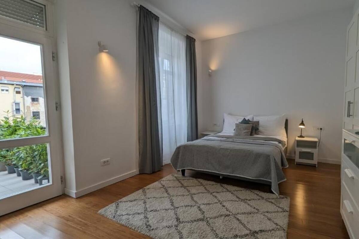 Ein Schlafzimmer mit Bett, Nachttischen, einem Fernseher und Blick ins Freie.