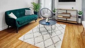 A modern living room with a green sofa, a round coffee table, a TV mounted on the wall, and a bookshelf. - Berry Berry studios by Flat White (Zagreb)